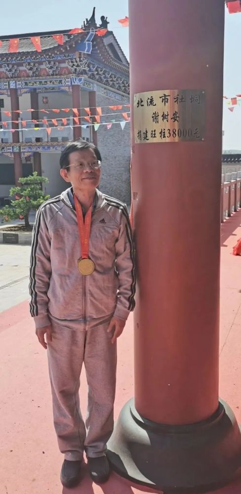 广西总会执行会长谢树安 在认捐的柱子旁边合影