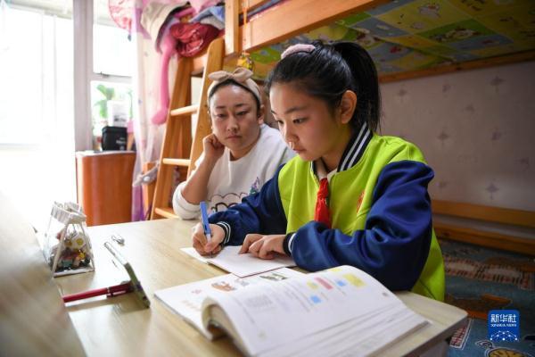 10月25日,宁夏银川市五年级学生安思雯(右)在妈妈的陪伴下学习线上