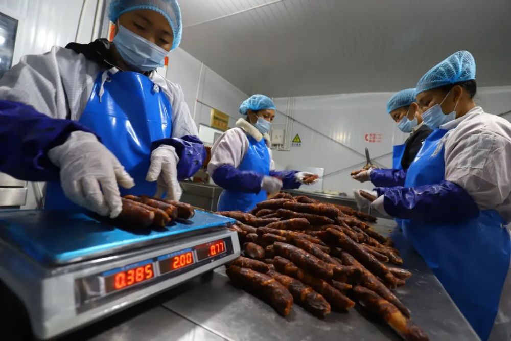 彝谷农产品有限公司扶贫车间内,工人们正忙着加工彝乡风味的腊肉腊肠