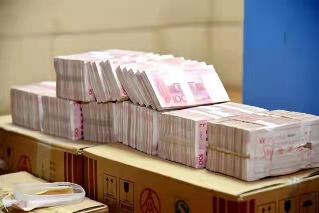 除了一沓沓整齐的百元现金外,标有贵州茅台,五粮液的纸箱引人注目