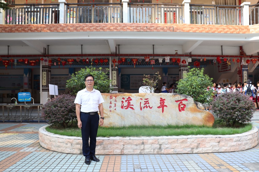 流溪小学校长陈志辉在百年流溪石碑前合影.