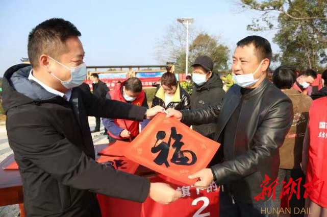 攸县书法协会志愿者现场为老百姓写春联,送"福"字;县摄影协会志愿者为