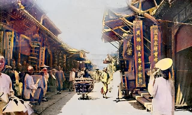 这张图片是北京清末时期的一处街景,商铺林立的街市上 人来人往,这里