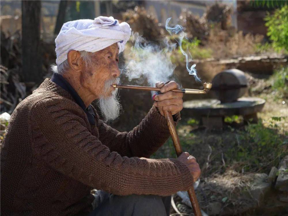 最开始是模仿村中的老人抽旱烟,就是把烤好的烟叶直接揉碎了卷起来抽