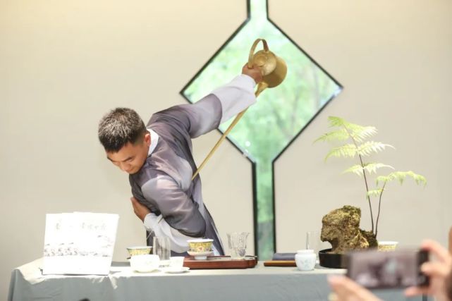 动作准确将水注入杯盏中提壶把盏翻转腾挪嘴长一米多的长嘴铜壶掺茶师