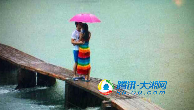 在雨中,一对恋人在沱江上拥抱接吻为雨中凤凰增添浪漫色彩.