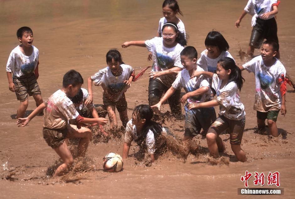 小学生暑期玩泥不怕脏 泥地踢足球不亦乐乎