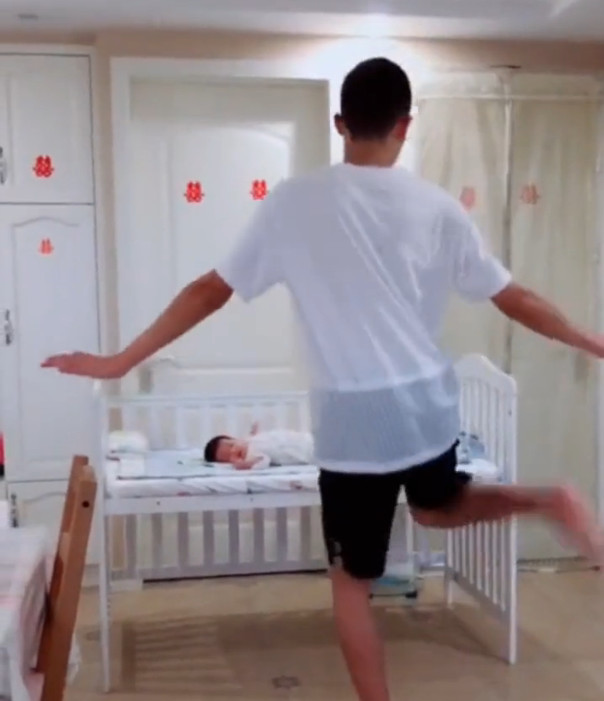 爸爸对着躺在婴儿床里的宝宝跳起舞来,动作特