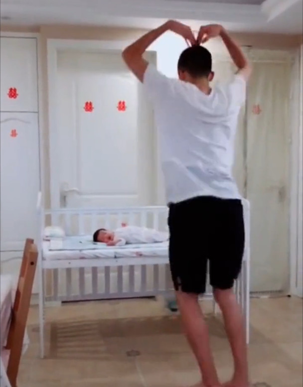 爸爸对着躺在婴儿床里的宝宝跳起舞来,动作特
