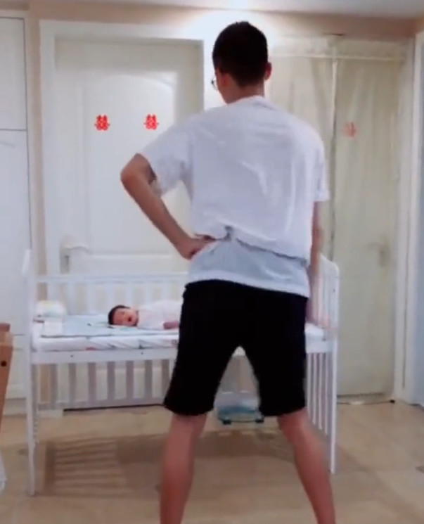 爸爸对着躺在婴儿床里的宝宝跳起舞来,动作特