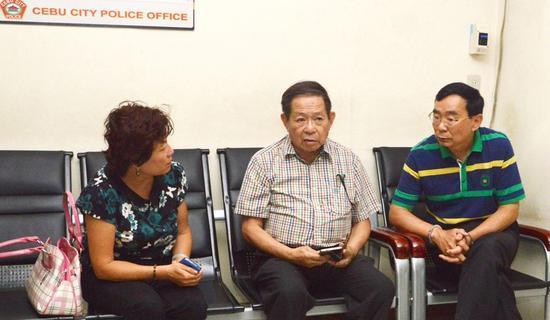图为涉案的两名中国人左一郭晶、右一带手铐李青良接受菲律宾警方调查