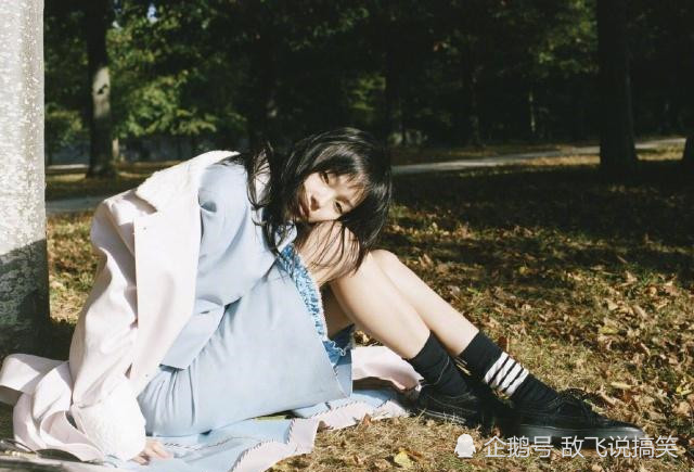 雎晓雯身穿蓝色的制服套装,外搭白色的一件长款外套,抱膝坐在地上