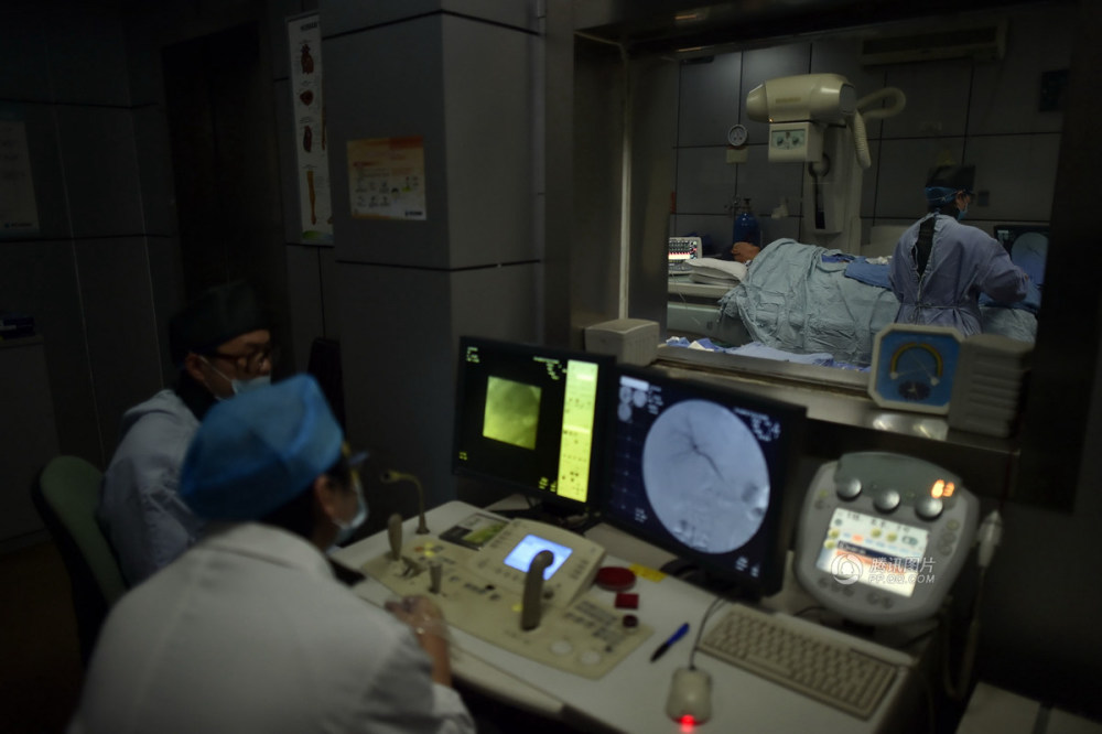 手术室里,穿上铅衣的刘亚在辐射中为病人进行介入手术.