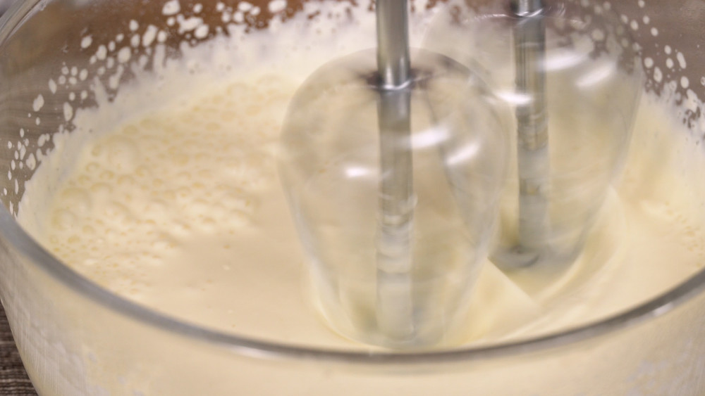 将牛奶倒入奶油奶酪中,搅拌均匀后再倒入打发好的淡奶油中,加1g盐