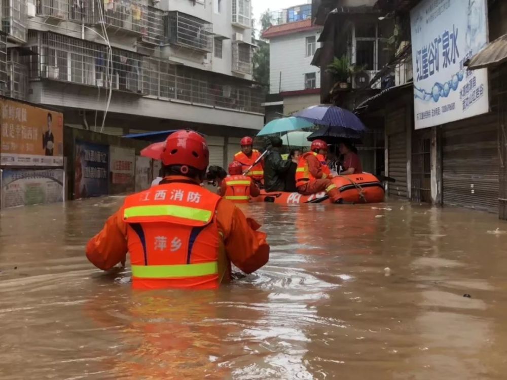 消防员到达现场,在暴雨中迅速将砂石装袋,协助大型机械将河堤筑牢.