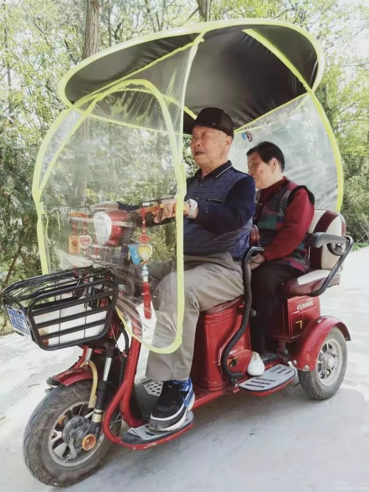 老人天天骑着电动车带着85岁的老伴上街走亲戚,过着惬意的生活.