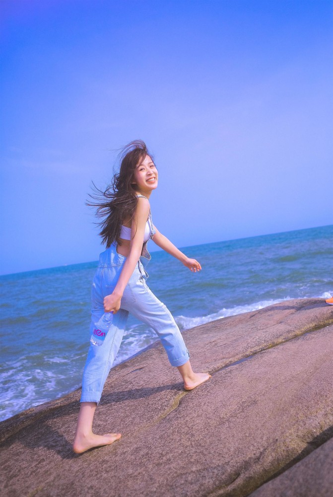 蓝色天空海边上,金色长发爱笑的女孩