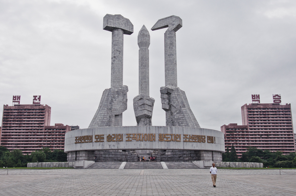 图为朝鲜平壤街头标志性的建筑,三只手举着三种不同的工具,象征着不同