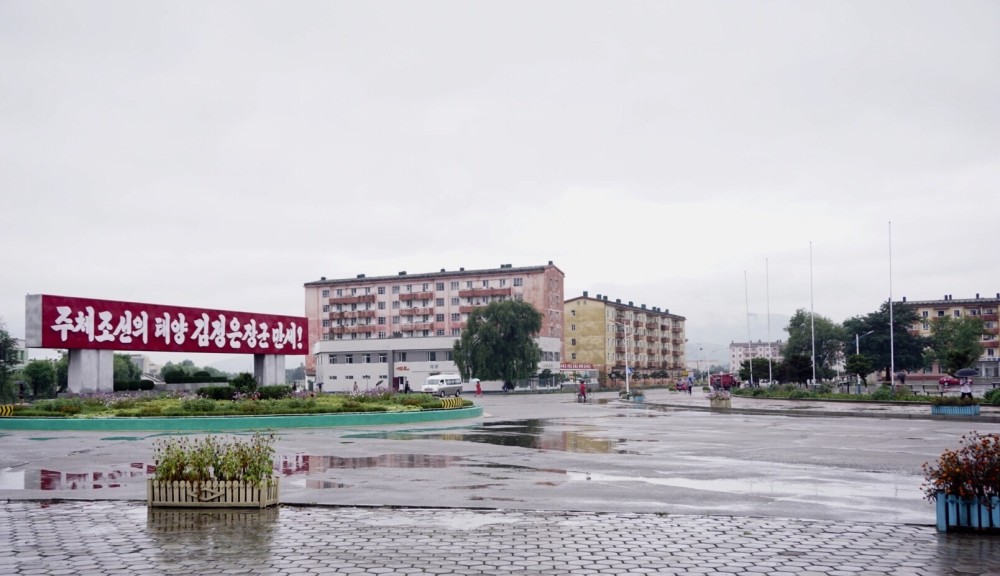 图为朝鲜南浦的街景,街上能见到宣传标语和海报,房屋都显老旧.