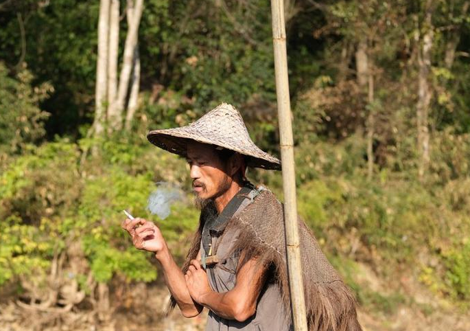 王利保头戴斗笠,身披蓑衣在渔船上娴熟的变