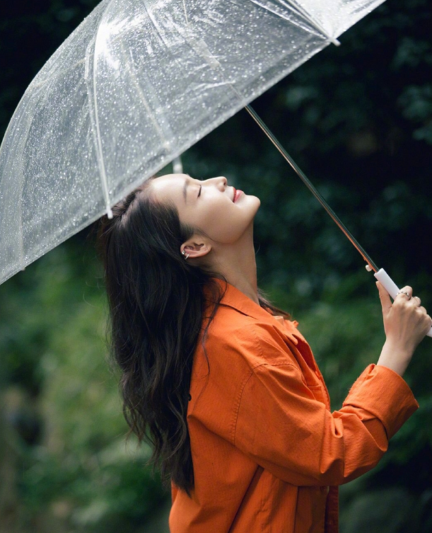 李沁穿橘黄色的衬衫,雨中撑着伞,美得不一样