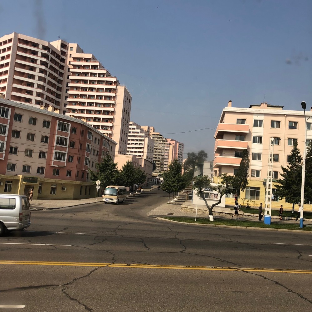 图为朝鲜平壤街头,马路两旁居民楼很多,街头的汽车不多.