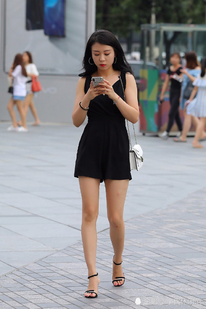 街拍:黑色吊带连衣裙的美女,边走路边玩手机!