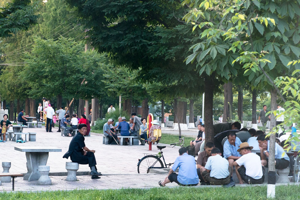 图为朝鲜平壤的一个公园,公园里休闲的人很多.老人们聚在一起下象棋.