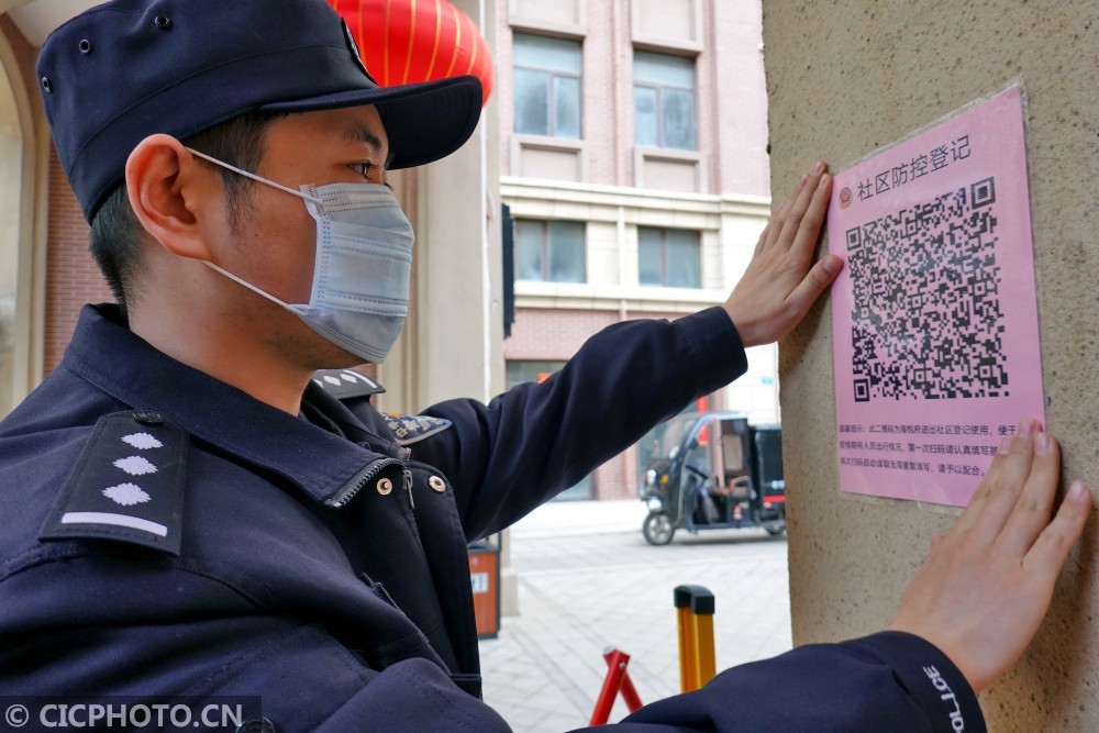 在山东省烟台市高新区一住宅小区,民警张贴"社区疫情防控登记"二维码
