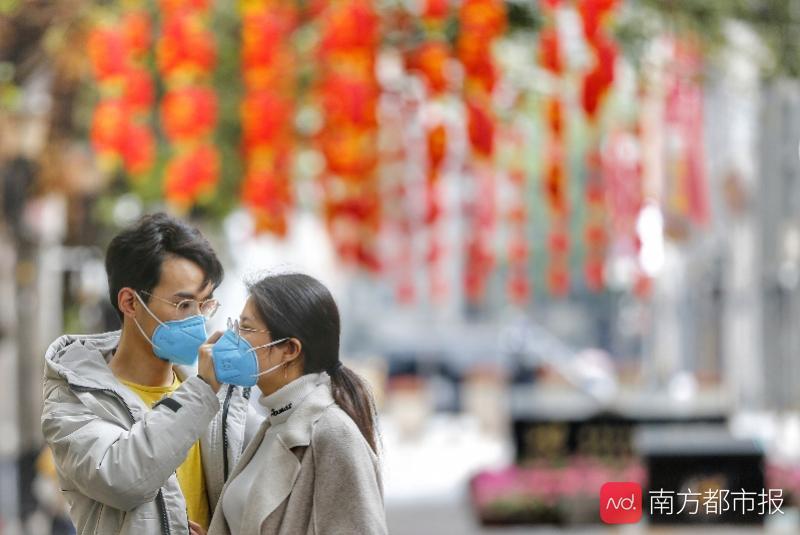 2月14日下午,广州北京路,一位男士为女伴整理口罩的耳扣.