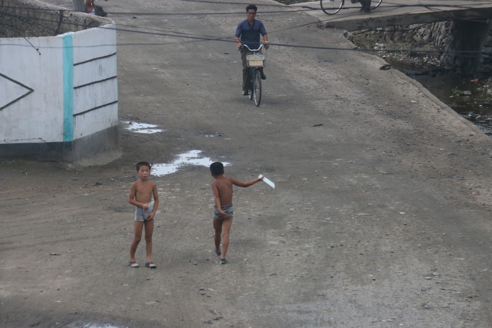 图为两名新义州小男孩,他们光着膀子在街头玩耍.