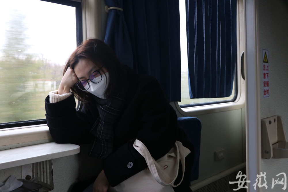 火车上,一名乘客戴着口罩坐在车窗边睡觉.