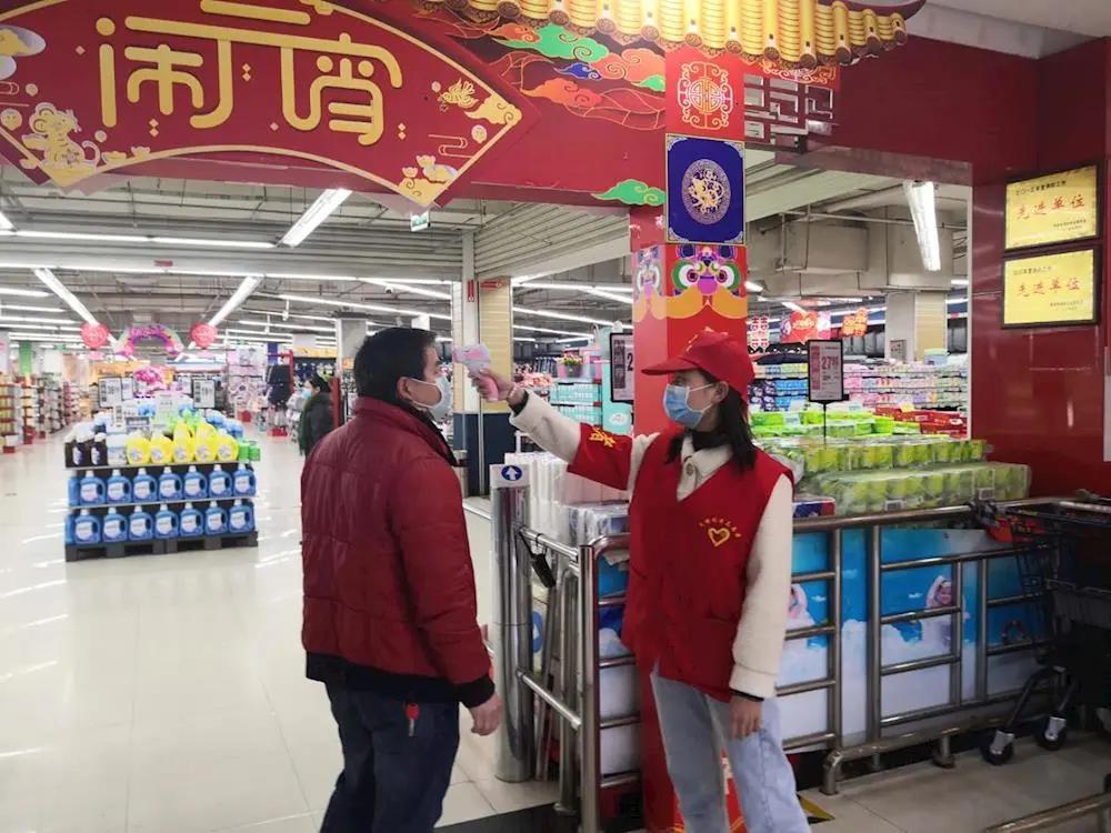 志愿者对超市进出人员进行体温检测