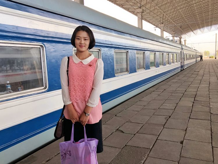 图为朝鲜火车站,一名年轻可爱的朝鲜女孩,她一头短发,微微笑着.