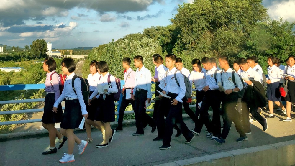 图为朝鲜平壤一座大桥上,一群朝气蓬勃的中学生走在桥上.