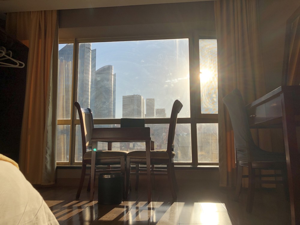 透过窗户可以看到晴朗的天气和周围高楼大厦,暖和的阳光直射到房间里