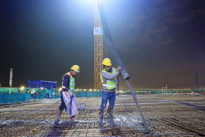 体育场第三层平台上,施工人员正在浇灌混凝土.