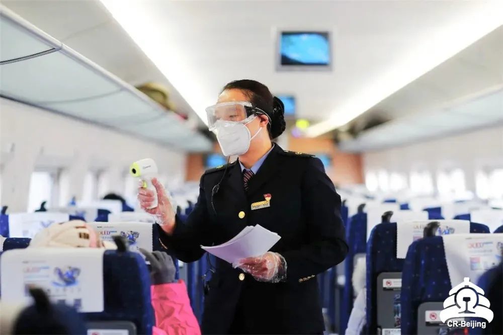 乘务员为旅客发放信息登记表和测温.