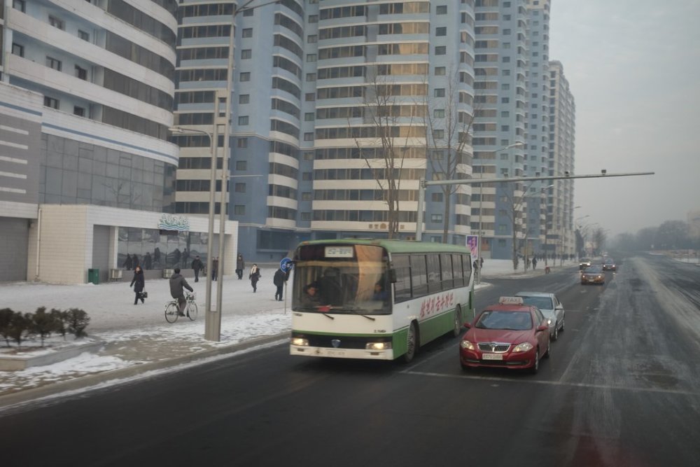 图为朝鲜平壤冬日街景,街上能见到出租车和公交车,还能见到骑自行车的