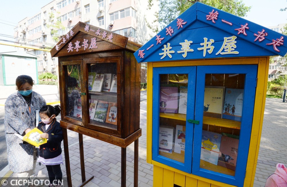 4月22日,在河北省邯郸市复兴区石化社区广场,居民在"流动共享书屋"旁