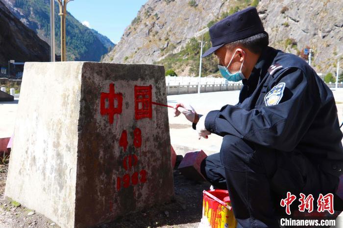 图为移民管理警察肖图友正在为中尼边界48号界桩描红. 郭章统 摄