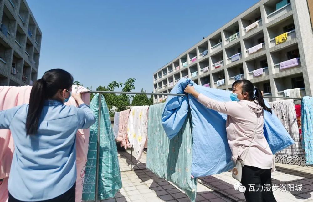 宿舍工作人员正加固晾衣绳,晾晒学生被褥.