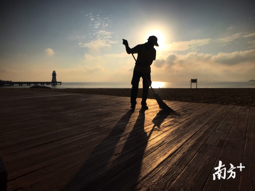 4月30日早晨,珠海海滨泳场附近,晨光映衬着清洁工人劳动的身影.