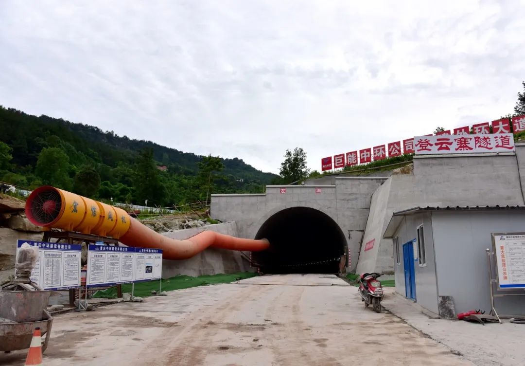 挖掘机舒展着铁臂忙着平整路基 搅拌车,运输车来回穿梭 隧道内,工人