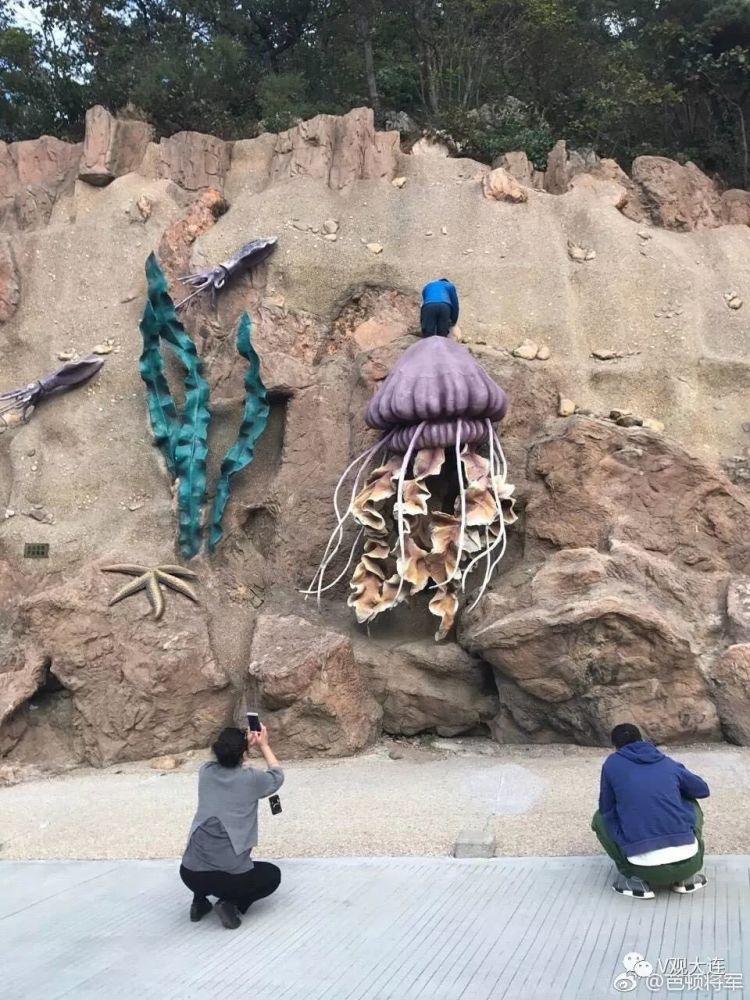 游客海之韵广场脚踩雕塑拍照 还摆各种奇特造
