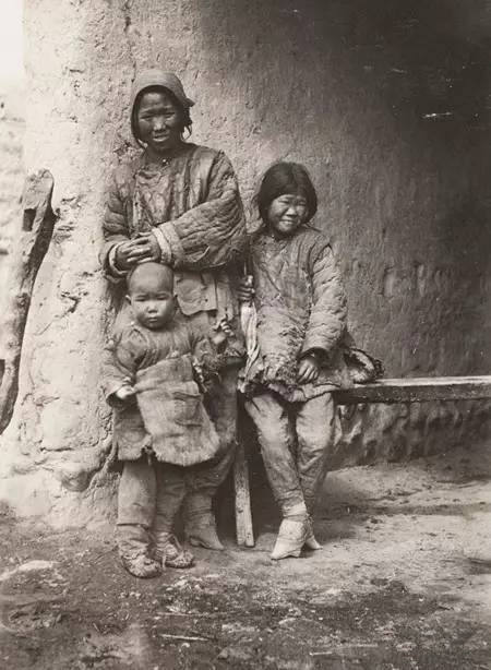 图为一个穷苦家庭,一个晚清妇女和一对子女,身上的衣服非常的破烂.