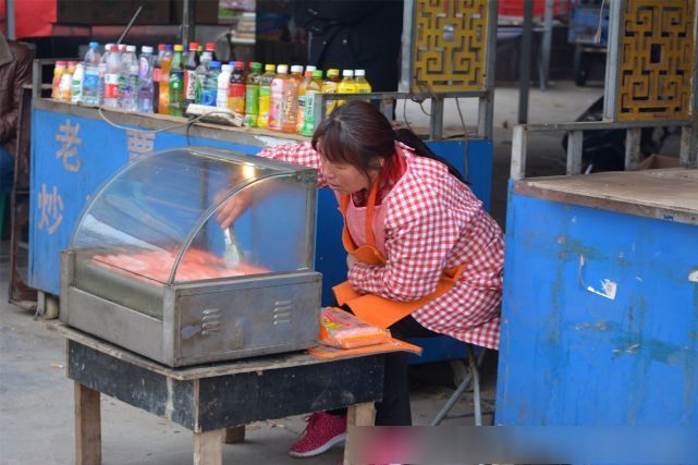 路边一边卖饮料,一边卖烤肠的女人,两块钱一根烤肠,客人不多,但一天也