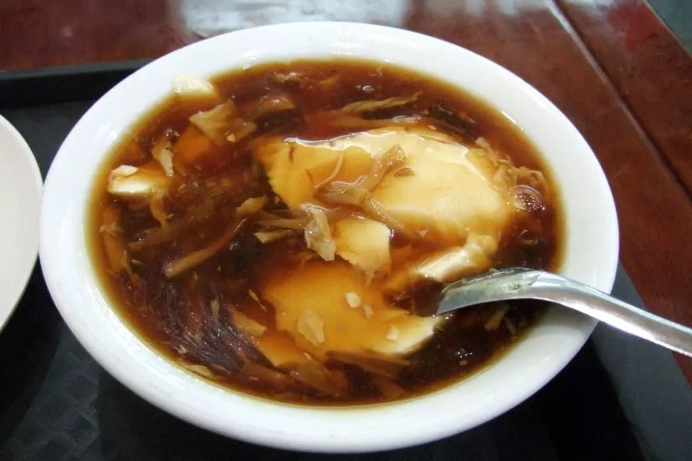 临泉豆腐脑传统的吃法是一半白色豆腐,一半咸味辣糊汤.