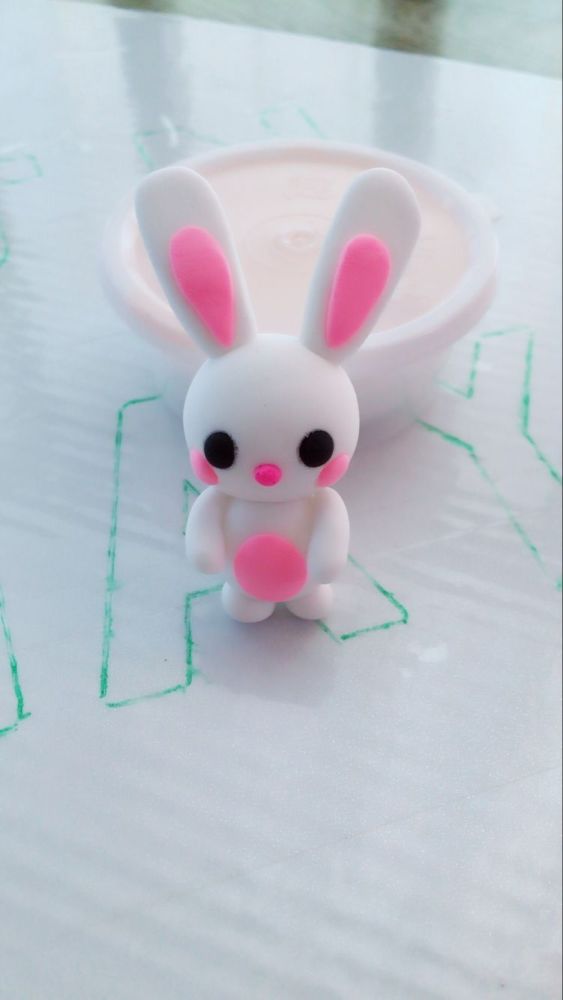 再取少量粉色粘土,揉搓成椭圆形,压扁,贴在白色身体上,做成兔子粉粉