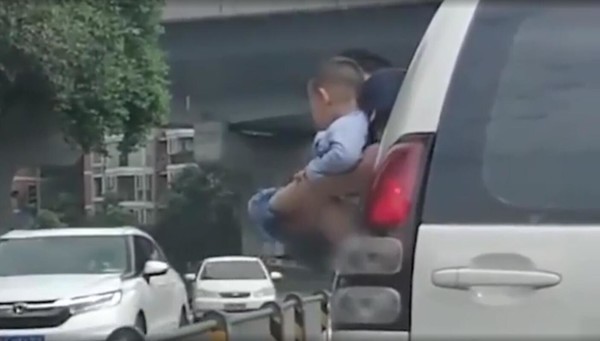 男孩被抱出车窗撒尿 网友:既不道德也很危险!